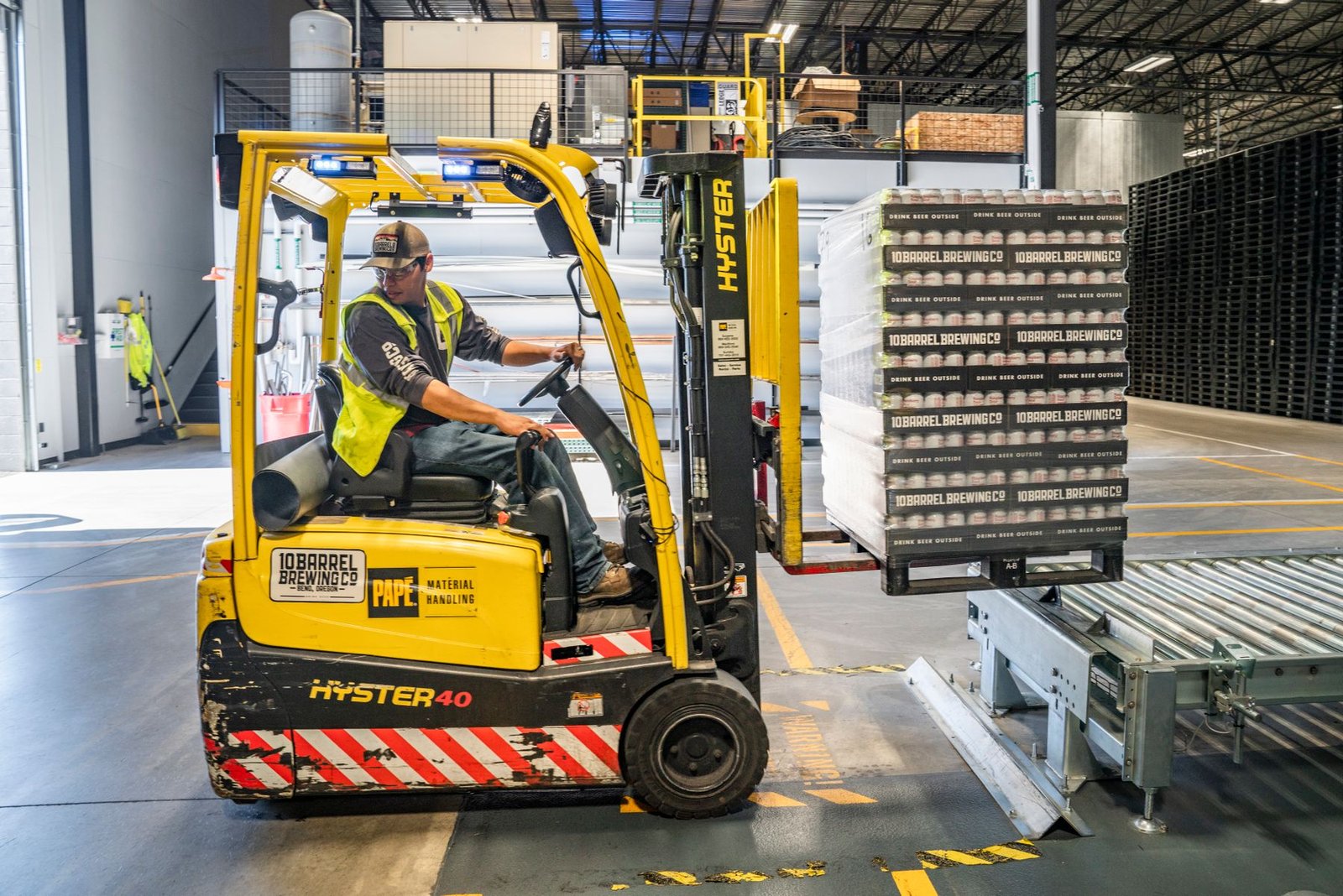 An operator drives a forklift in a working warehouse.